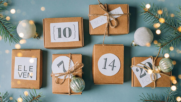 Christmas Boxes with numbers and decorations representing Advent calendar on a blue-grey surface